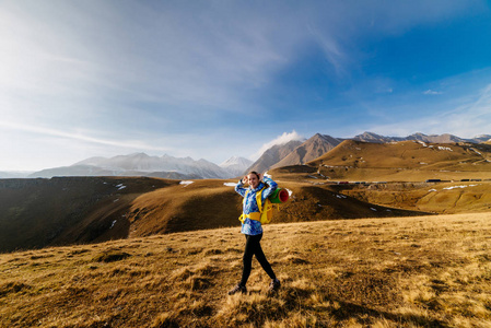 穿着蓝色夹克的活跃运动女孩沿着高加索山脊旅行, 背包和帐篷