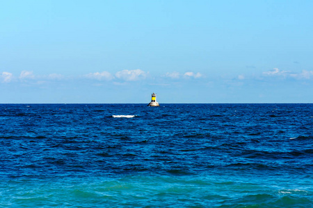 海景.蓝色的海和天空。在背景一个小灯塔