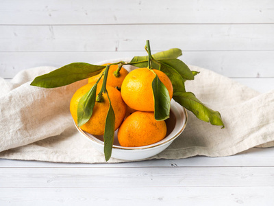 新鲜的普通话或柑橘与茎和叶子在板材在白色木背景拷贝空间