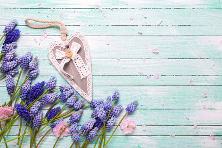 框架与粉红色的杏仁和蓝色的 muscaries 花和心脏的绿宝石木背景。文本的位置。选择性焦点