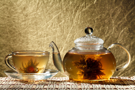 玻璃茶壶和金色背景上的一杯绿茶