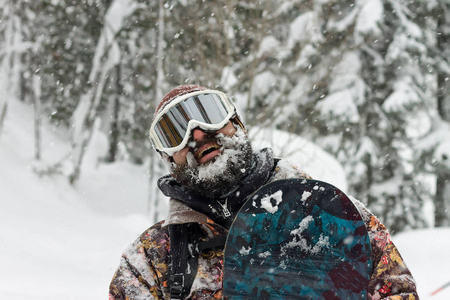 在山中手持滑雪板的肖像大胡子男子滑雪护目镜