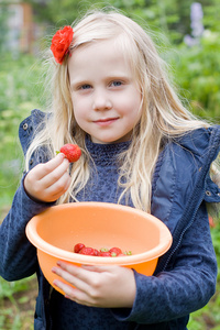 花园里有红色草莓的漂亮女孩