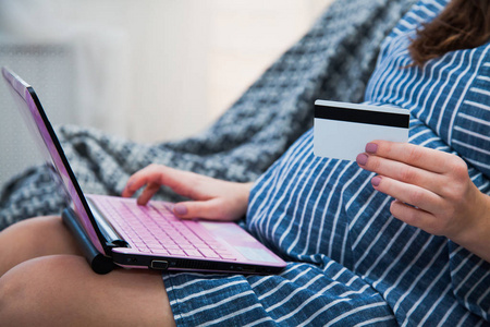 年轻孕妇网上购物与笔记本电脑信用卡特写