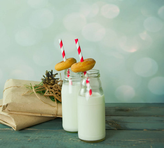 圣诞礼物, 手套, 瓶子里的牛奶和木桌上的小甜甜圈