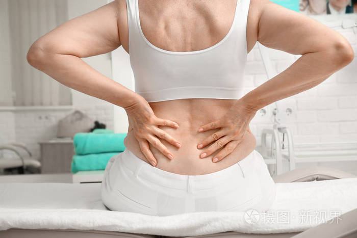 坐在按摩台上的老年妇女背部疼痛