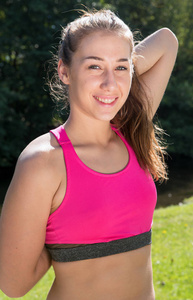 年轻女子运动的女孩与粉红色顶部锻炼户外