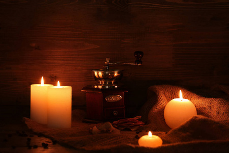 在黑暗中的桌子上燃烧蜡烛和咖啡磨床