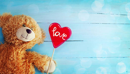 可爱的泰迪熊和商会糖果心脏在木头背景