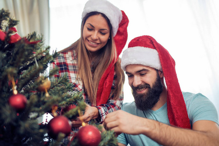 装饰圣诞树在他们的家中对快乐的夫妻
