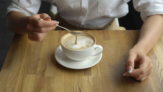 一个年轻美丽的女人，在一家咖啡馆里喝咖啡。在业务上午休的衣服的年轻女子