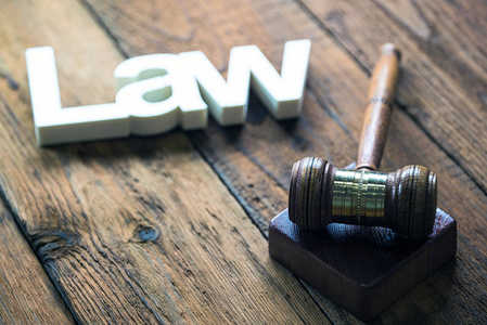 法律概念   开放法律书籍用木制法官木槌在蓝色背景上法庭或法律执法办公室的桌子上。复制文本的空间