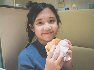 在餐馆吃汉堡包的可爱的亚洲女孩