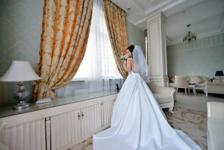 美丽的新娘在婚纱与花束和蕾丝面纱在室内