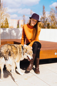 年轻美丽的 redhaired 女孩在一个时髦的橙色毛衣是散步与她的狗在公园