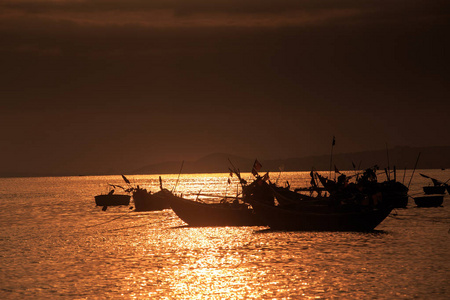 越南渔船剪影在明亮的阳光反射太阳路在日落
