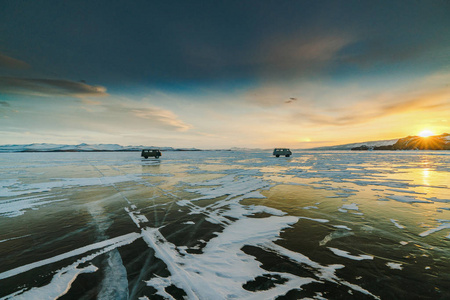 在日落时, 两辆汽车在贝加尔湖冰上的图案。西伯利亚俄国