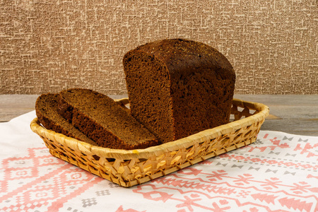 在一个篮子里站在一条毛巾上切片黑麦面包。一条木制仿古桌上片新鲜黑麦面包