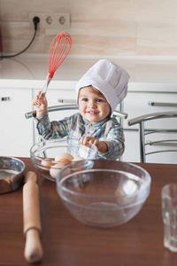 愉快的小孩子在厨师帽子与扫和蛋在碗