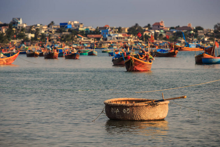 在日落时, 在宁静的海洋海湾与船桨的棕色越南圆形木制渔船特写
