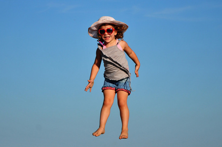一个漂亮的小女孩在海滩上玩耍和跳跃