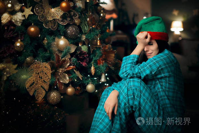 伤心难过的寂寞女孩在她的圣诞树旁哭泣