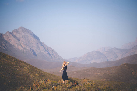 美丽的金发女模特站在山上欣赏风景