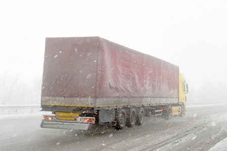 在冬天的降雪中的道路上的卡车