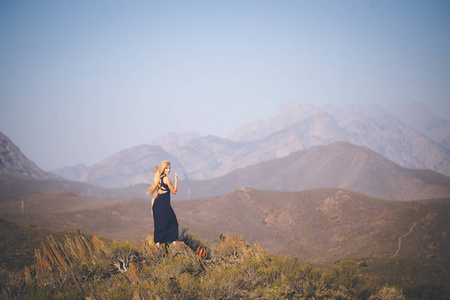 美丽的金发女模特站在山上欣赏风景