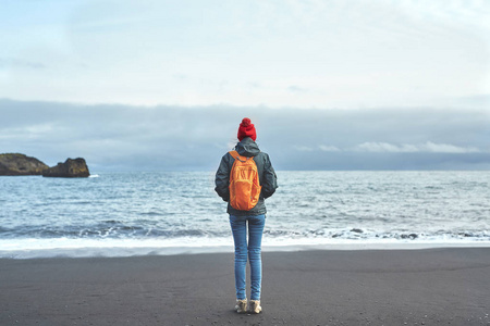 走在 Kirkjufjara 黑沙海滩，冰岛南部的女人