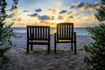 日落时分面对大海的沙滩椅夫妇