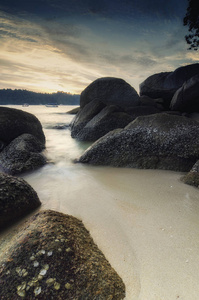 日落时田园诗般的热带岛屿风光, 海浪拍打海岸的岩石