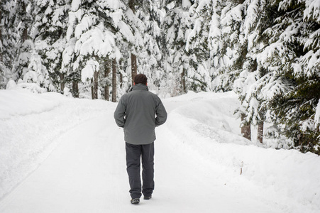 成年男子步行在森林雪