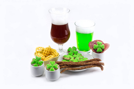玻璃杯深色啤酒, 绿色三叶草板与开胃肉薯条在白色的背景。圣帕特里克节