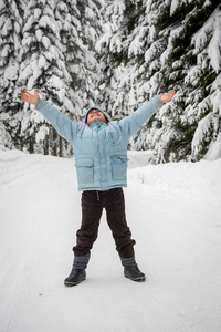 男孩走在白雪皑皑的乡间森林之路