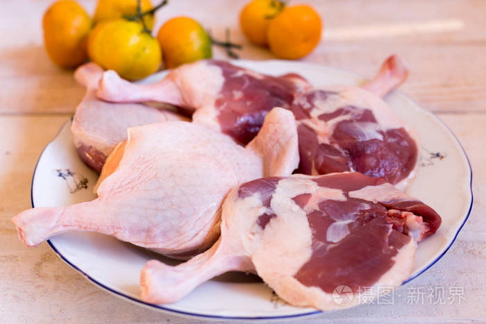 鸭肉新鲜,原始的鸭腿与在木质表面上的水果