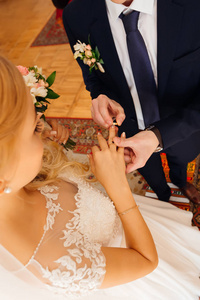 新郎把结婚戒指放在新娘的手指上。新婚夫妇 f