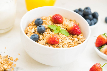 健康早餐在白色石桌背景设置燕麦饼与蓝莓和草莓和黑咖啡牛奶和橙汁