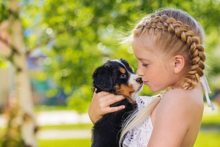 可爱的小女孩拥抱逗人喜爱的小狗摆在绿色庭院