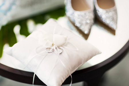 白色枕头与结婚戒指和结婚鞋在桌上