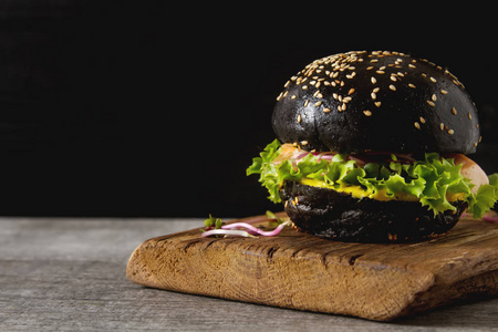 黑色汉堡配三文鱼 生菜 芥菜。黑暗的背景