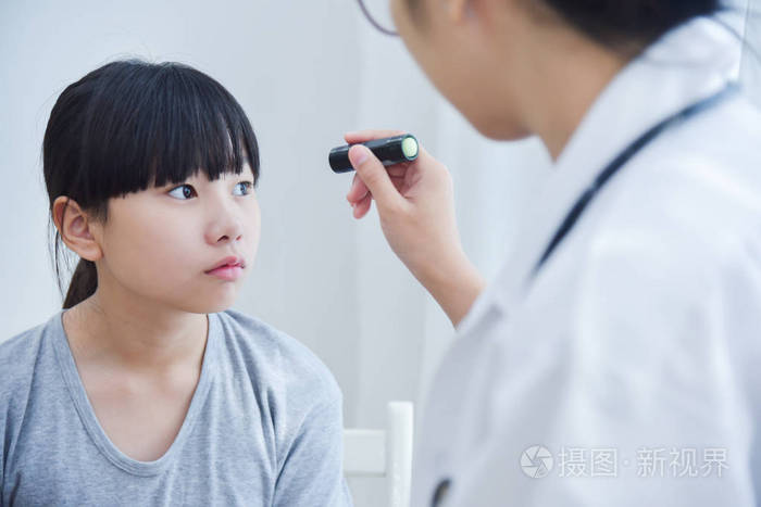 医生戴眼镜检查一个小女孩的病人的眼睛