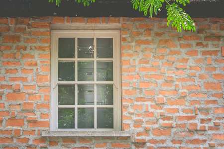 在老式风格的房子顶部的棕色砖墙上关闭旧的白色窗口