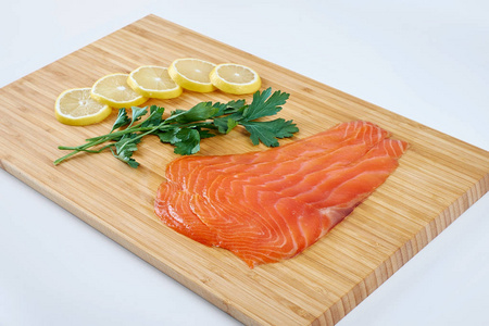鱼片熏鳟鱼与新鲜的草药和柠檬在一块木板上。海鲜, 隔离