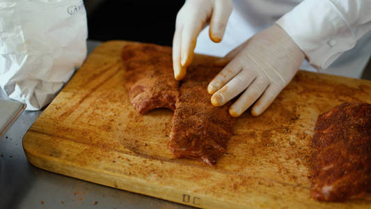 特写的专业厨师人准备香料在餐厅厨房砧板上的肉排骨