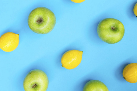 蓝色背景下新鲜柠檬和苹果的彩色水果图案