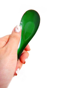 女人手里拿着一把勺子修剪过的花岗岩钉子。在白色背景上关闭绿色锌勺