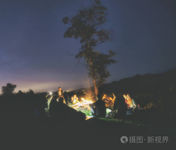 年轻人的公司围坐在篝火旁