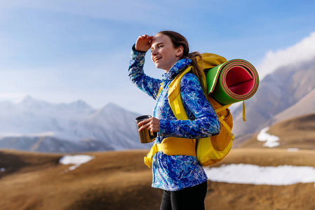 穿着蓝色夹克的快乐小女孩沿着高加索山脊旅行, 喝一杯热水瓶里的茶