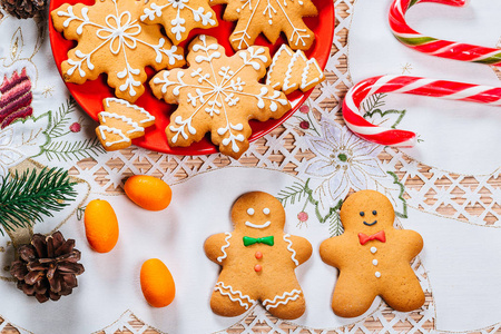 圣诞姜饼饼干自制的红盘子与树枝的圣诞树和装饰在家里的新年表。圣诞快乐明信片